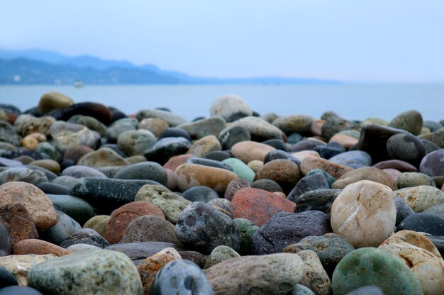 Piedras de guijarros naturales multicolores en la playa con paisaje marino