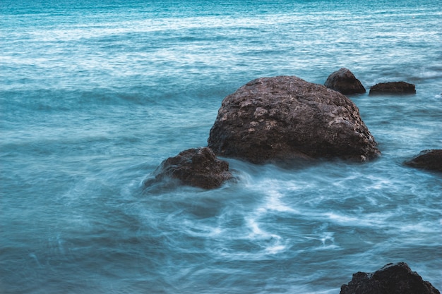 Piedras en el mar con olas de larga exposición