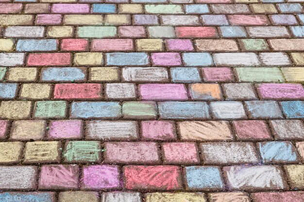 Las piedras de pavimento pintadas con colorida tiza de calle