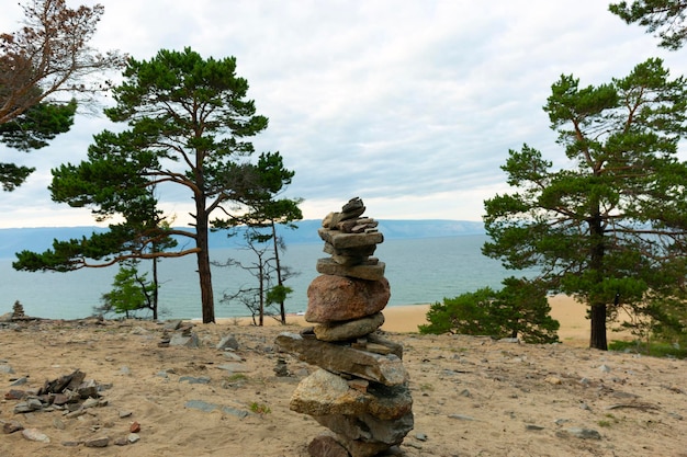 Piedras piramidales zen y alerces en la playa de arena del Baikal