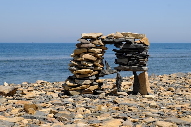 Foto piedras planas intrincadamente apiladas en una pirámide a la orilla del mar.