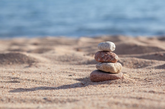 Las piedras redondas se encuentran una encima de la otra en una columna a orillas del mar en un día soleado de verano