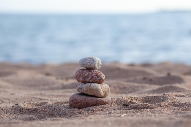 Las piedras redondas yacen una encima de la otra en una columna a la orilla del mar en un día soleado de verano.