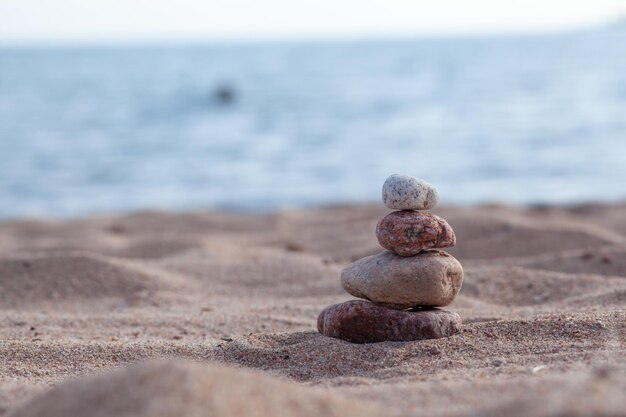 Las piedras redondas yacen una encima de la otra en una columna a la orilla del mar en un día soleado de verano.