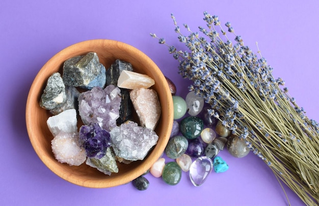 Piedras semipreciosas en un cuenco de madera con un ramo de lavanda seco