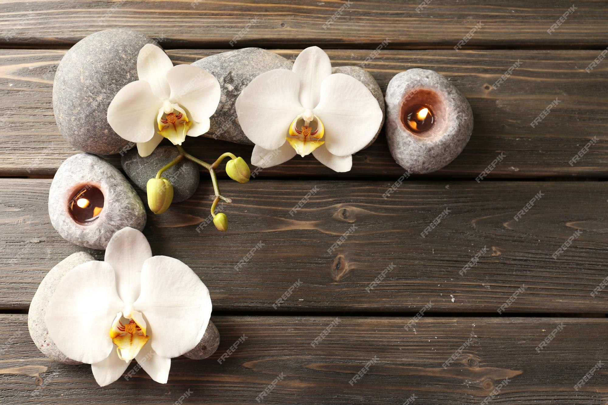 Piedras de spa y flor de orquídea sobre fondo de madera | Foto Premium