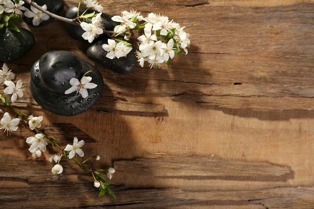 Piedras de spa con flores de primavera sobre fondo de madera