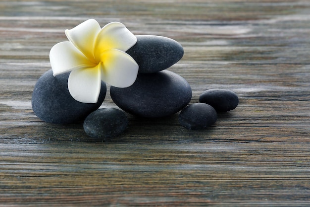 Piedras de spa con flores sobre un fondo de madera