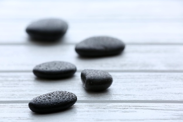 Piedras de spa con gotas de agua en fondo de madera