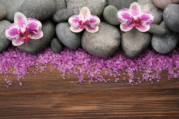 Piedras de spa y orquídeas en mesa de madera