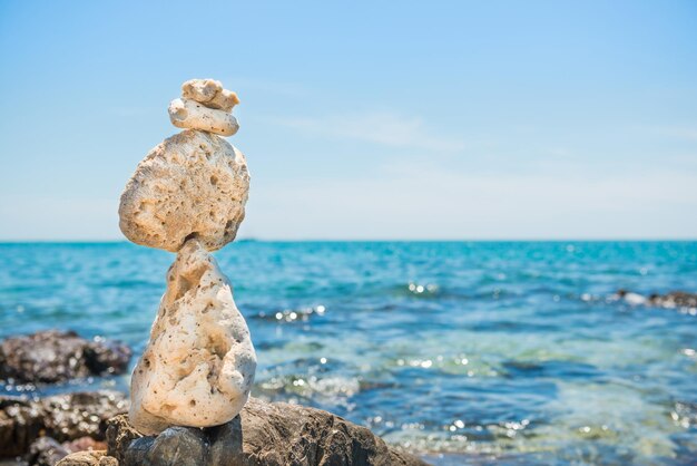 Foto las piedras zen se equilibran en la playa de piedras y el fondo del mar