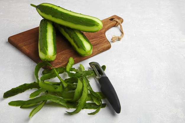 Con piel y cuchillo sobre una tabla de cortar de madera marrón sobre una mesa de hormigón gris claro