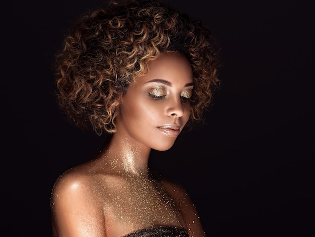 Piel de oro - mujer afroamericana - concepto de maquillaje hermoso peinado de belleza. Tiro del estudio.