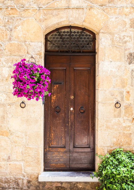 Foto pienza, región de toscana, italia. puerta antigua de madera con flores.