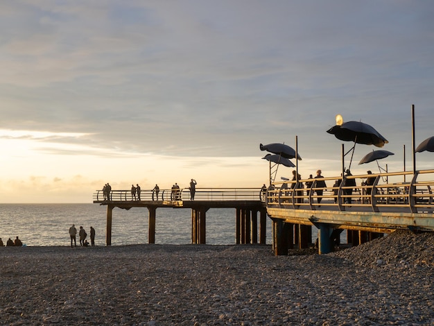 Pier am Strand mit Sonnenschirmen Pier in den Strahlen der untergehenden Sonne