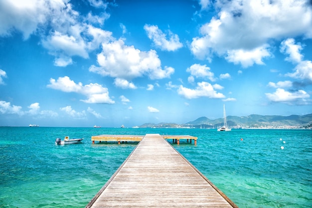 Pier im türkisfarbenen Meer und blauer Himmel mit weißen Wolken in Philadelphia, Sint Maarten. Freiheit, Perspektive und Zukunft. Strandurlaub in der Karibik, Fernweh.