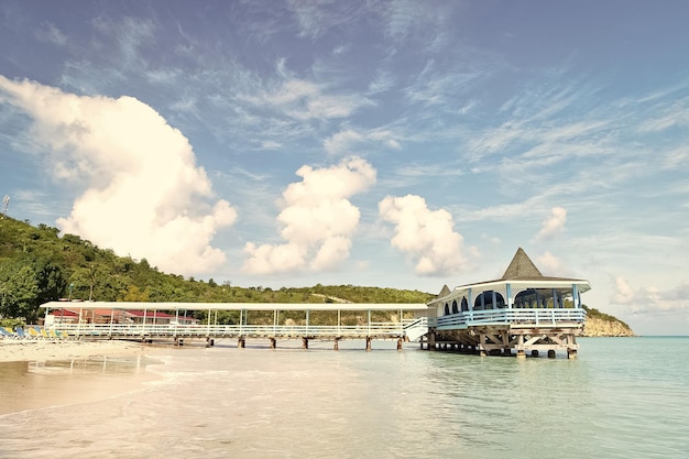 Pier in türkisfarbenem Wasser auf blauem Himmelshintergrund Meeresstrand mit Holzhütte an einem sonnigen Tag in Antigua Sommerurlaub in der Karibik Wanderlust-Reise Abenteuer-Entdeckungsreise