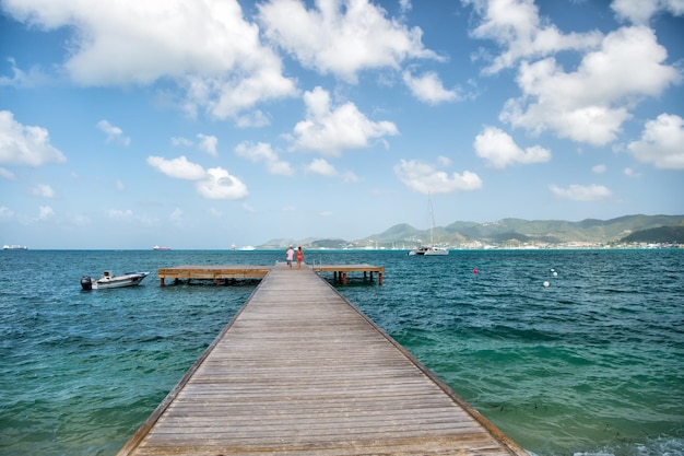 Pier mit Holzdeck im Meer- oder Ozeanwasser in Philipsburg, St. Maarten am bewölkten Himmel. Sommerurlaub in der Karibik. Perspektive, Reisen, Fernweh