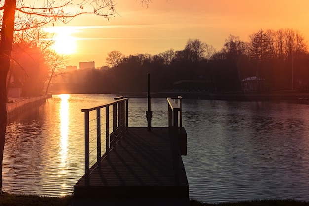 Píer no lago no parque da cidade pôr do sol de outono um lindo caminho de sol na água