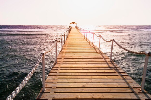 Foto pier no mar paisagem de ponte arborizada no porto entre o nascer do sol