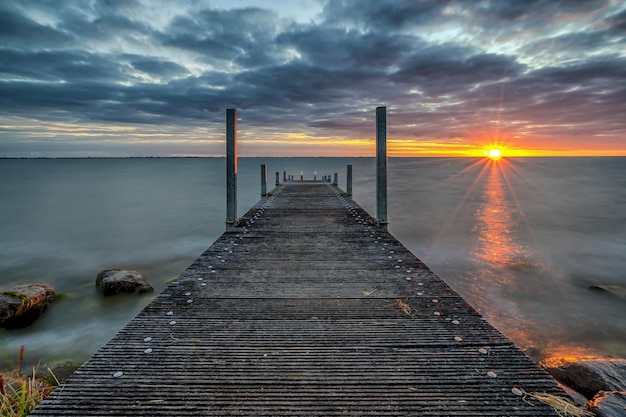 Pier über dem Isselmeer gegen bewölkten Himmel beim Sonnenuntergang