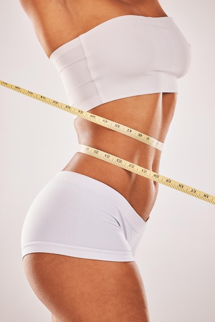 Pierda el cuerpo y la mujer de peso con cinta métrica en el estómago para la salud y el bienestar de la dieta Fondo de estudio de modelo saludable para el objetivo de fitness y motivación en ropa interior para resultados de ejercicio y progreso