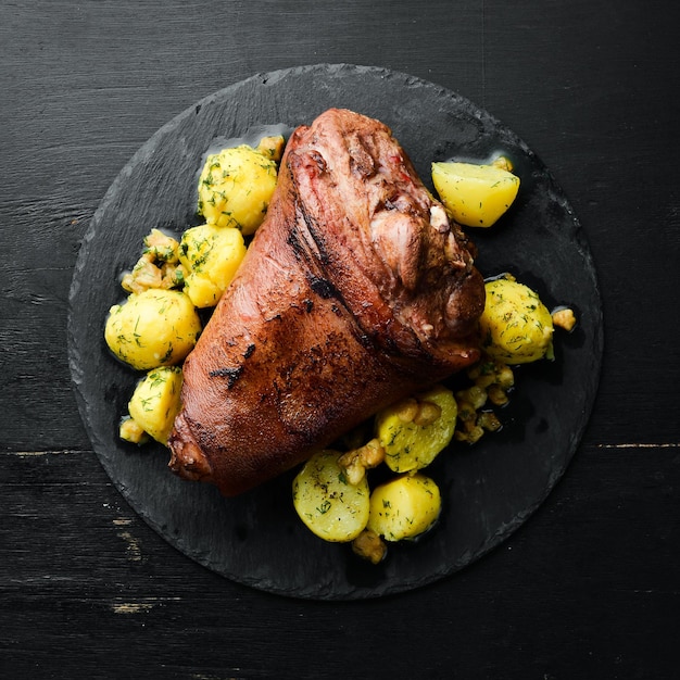 Pierna de cerdo al horno con patatas en un plato de piedra negra Bistec a la pimienta Vista superior espacio libre para el texto Estilo rústico