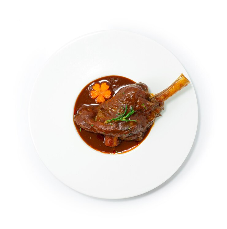Pierna de cordero estofada con salsa de vino tinto y verduras hasta que estén tiernas y triturables.