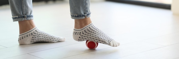 Pierna femenina en calcetines en la pelota de goma de masaje en el piso entrenamiento de masaje de pies de primer plano