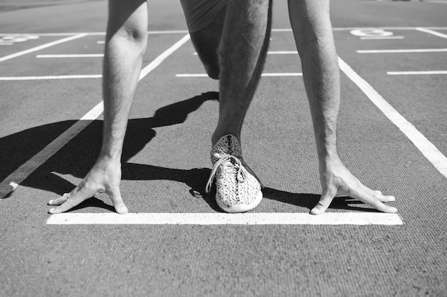 La pierna del hombre inicia la competencia corriendo en la pista de la arena, el verano soleado, el entrenamiento al aire libre y el deporte de la salud