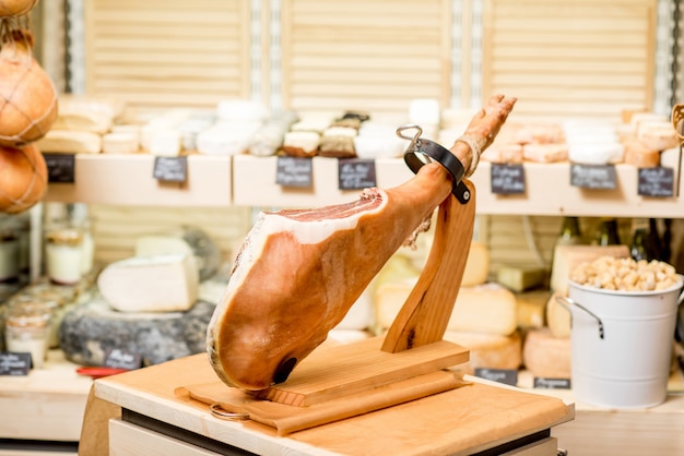 Pierna de jamón serrano en soporte jamonero sobre la mesa en la tienda de alimentos