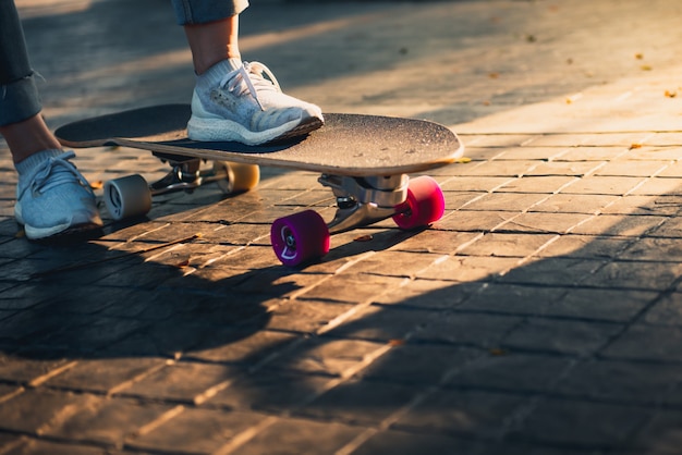 Pierna de mujer en patines de surf en la carretera