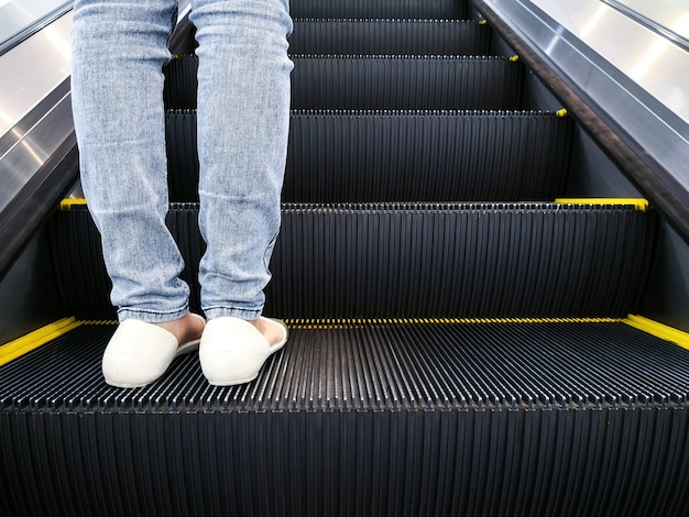 Pierna de mujer que viaja en la escalera mecánica.