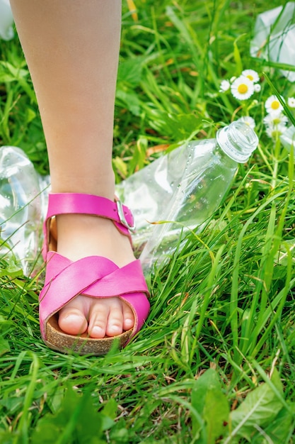 La pierna de una niña pisotea una botella de plástico