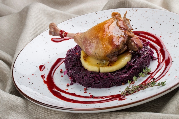 Foto pierna de pato con manzana y repollo sobre fondo textil