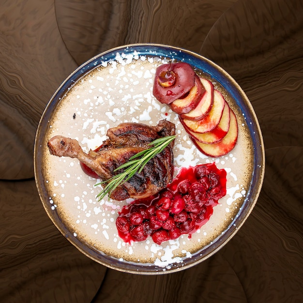 Pierna de pato con salsa de cereza y manzana al horno sobre un fondo de madera