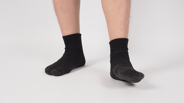La pierna y el pie asiáticos usan calcetín negro sobre fondo blanco. aislado