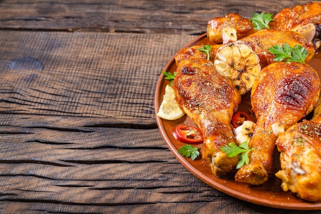 Pierna de pollo frito en un plato con condimentos sobre un fondo de madera oscura.