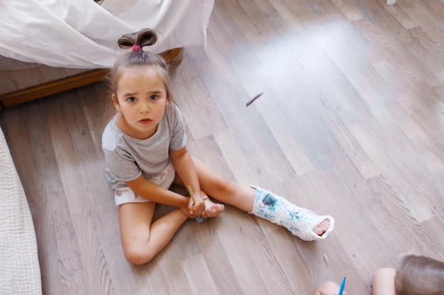 Pierna rota daño a los huesos un niño pinta un yeso una niña con un marcador