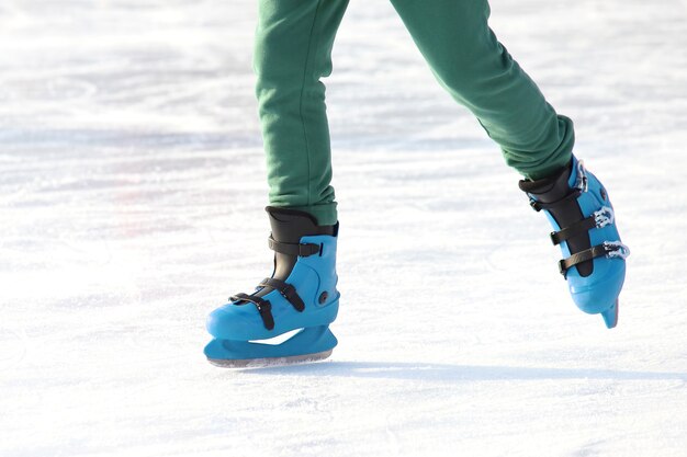 Piernas en azul patinando en la pista de hielo. deportes, pasatiempos y recreación de personas activas