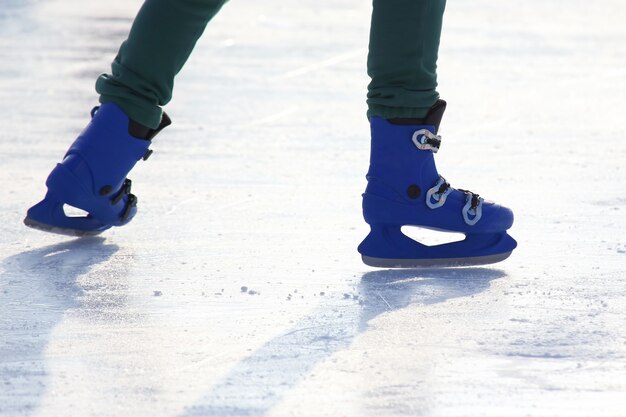 Piernas en azul patinando en la pista de hielo.