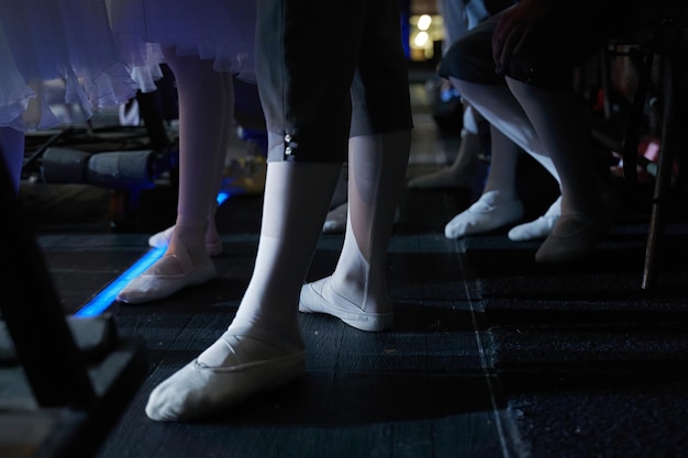 Foto piernas de una bailarina de ballet de pie entre bastidores con zapatos de punta