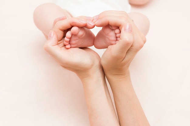 Las piernas del bebé en las manos de la madre tienen forma de hogar, corazón