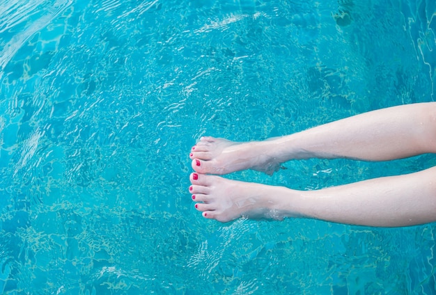 Piernas de belleza de mujer en la piscina