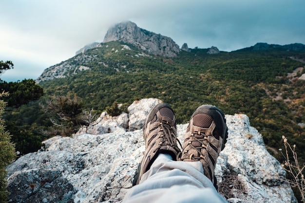 Piernas con bots de senderismo frente al paisaje montañoso con nubes