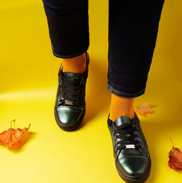 Piernas en calcetines amarillos y zapatillas de deporte sobre un fondo amarillo