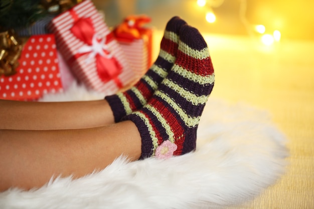 Piernas en calcetines cerca del árbol de Navidad en carped