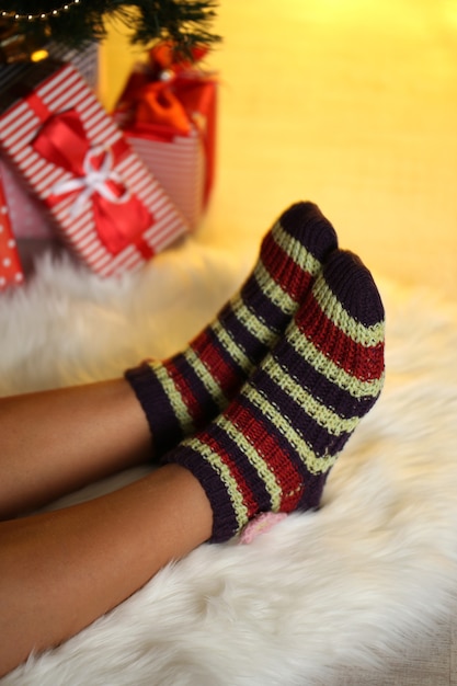 Piernas en calcetines cerca del árbol de Navidad en carped