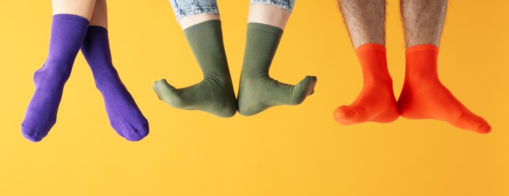 Foto piernas en calcetines diferentes sobre fondo amarillo