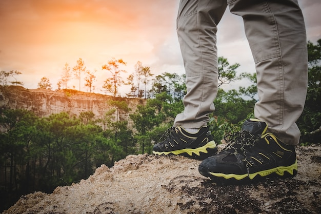 piernas del caminante del hombre en el pico de la montaña del amanecer